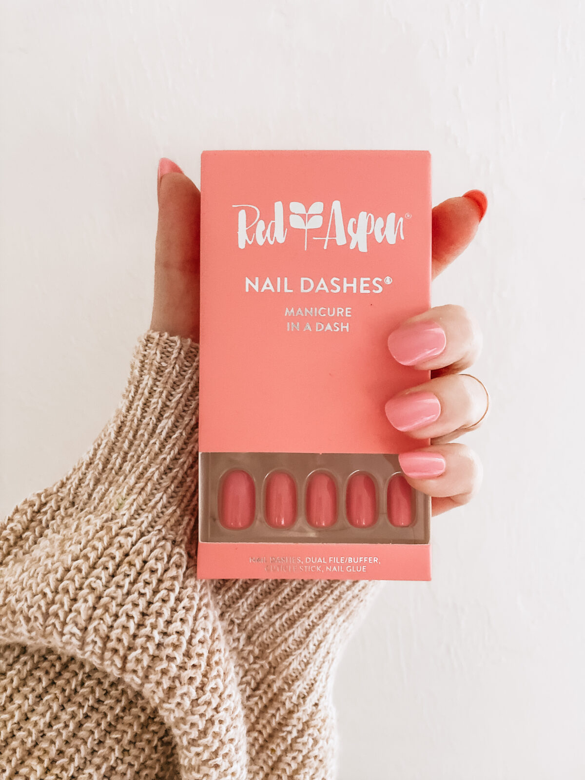 hand with red aspen manicure holding box of nail dashes
