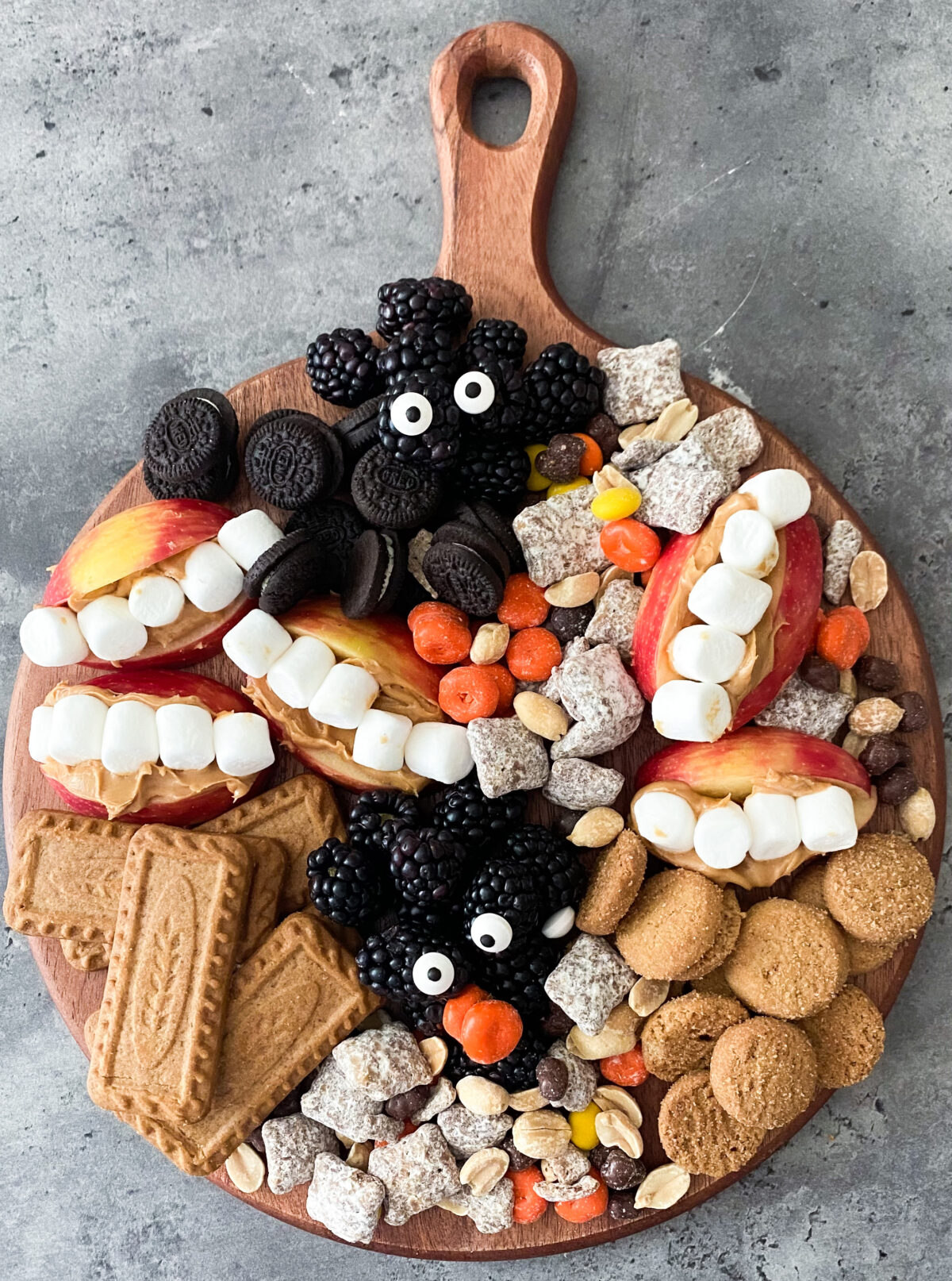 Halloween snack board charcuterie with monster mouth treats, fruit, chow mix, and cookies.