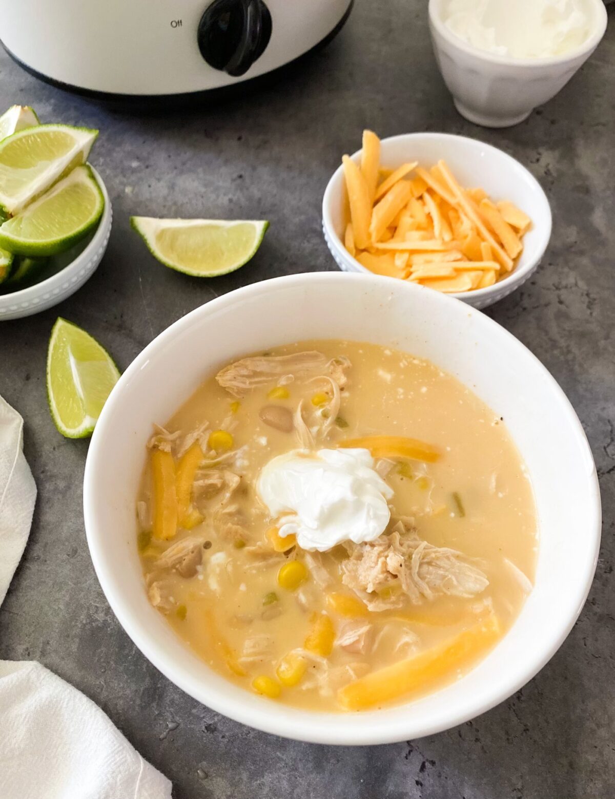 slow cooker white chicken chili in bowl with limes and cheese shreds