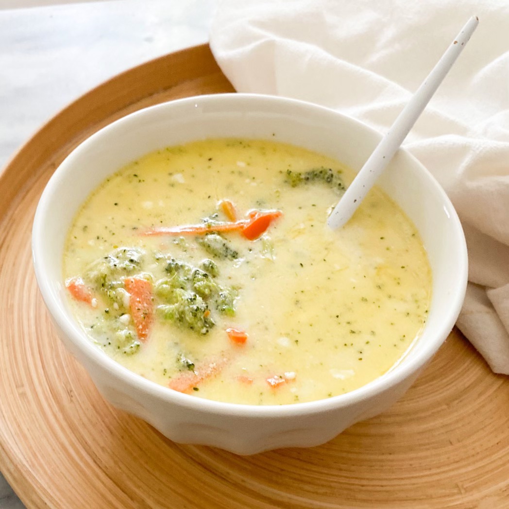 broccoli cheddar soup in bowl with spoon sitting on a serving tray