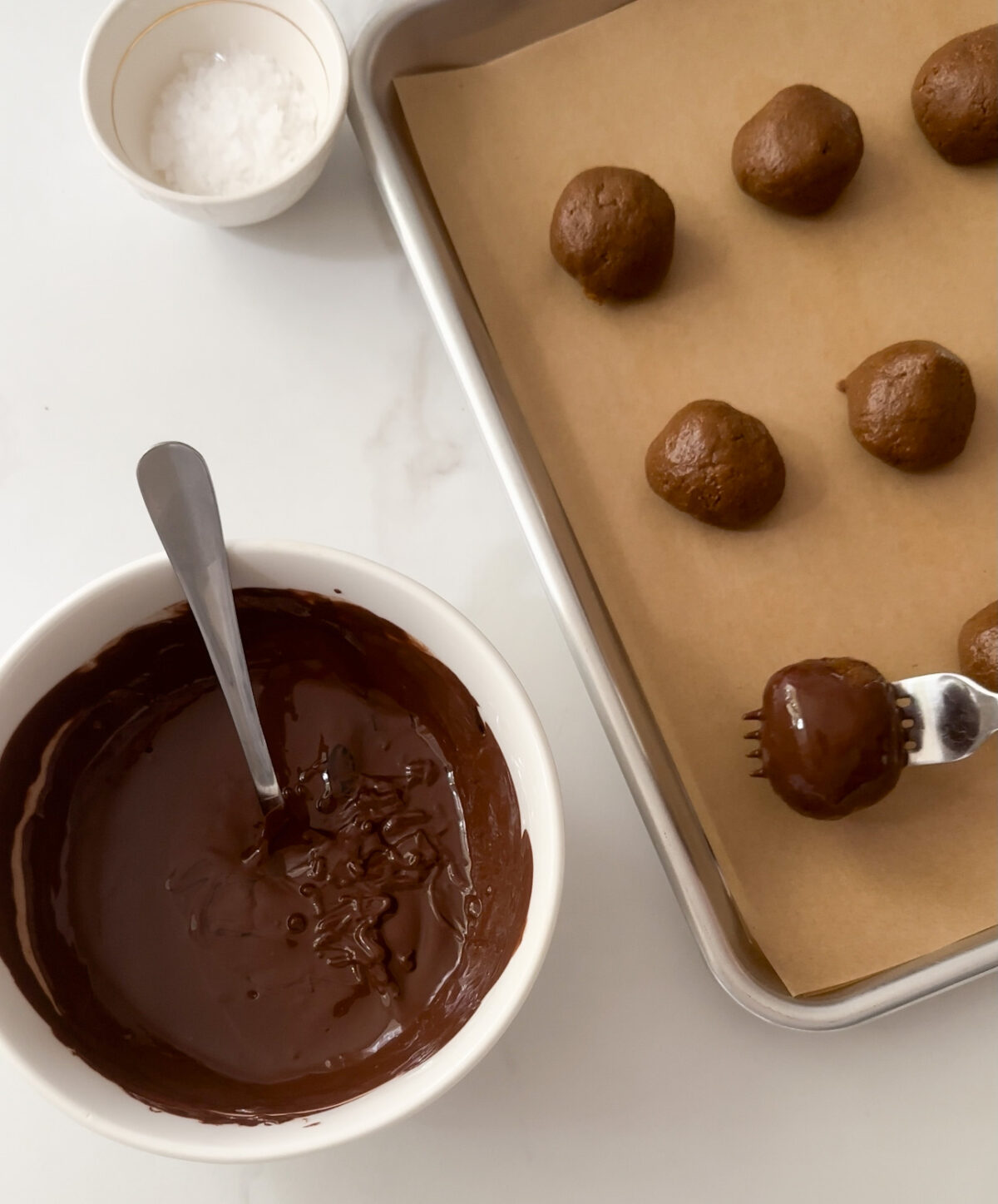 use a fork to dunk cookie balls into melted chocolate
