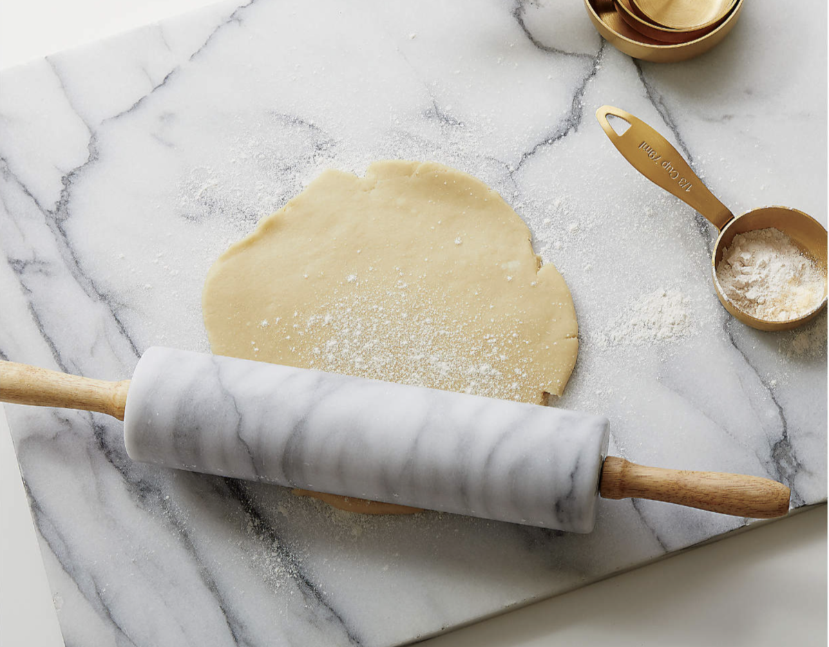 a marble rolling pin on marble board being used to roll out dough